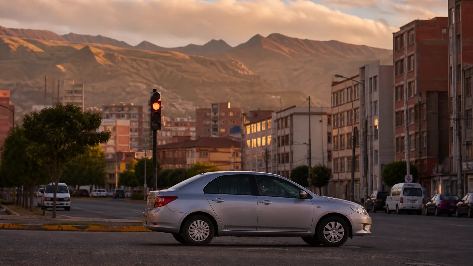 Carro particular esperando en un semáforo de una avenida de Bogotá al final de la tarde, con edificios y cerros al fondo